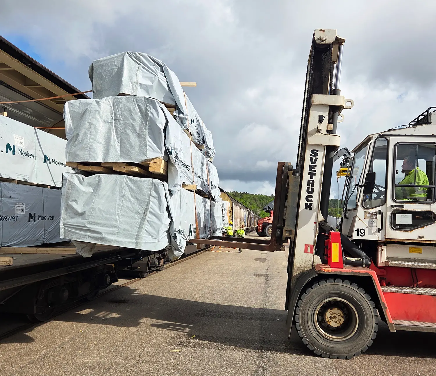 Lossning virkeståg från tåg med gaffeltruck.